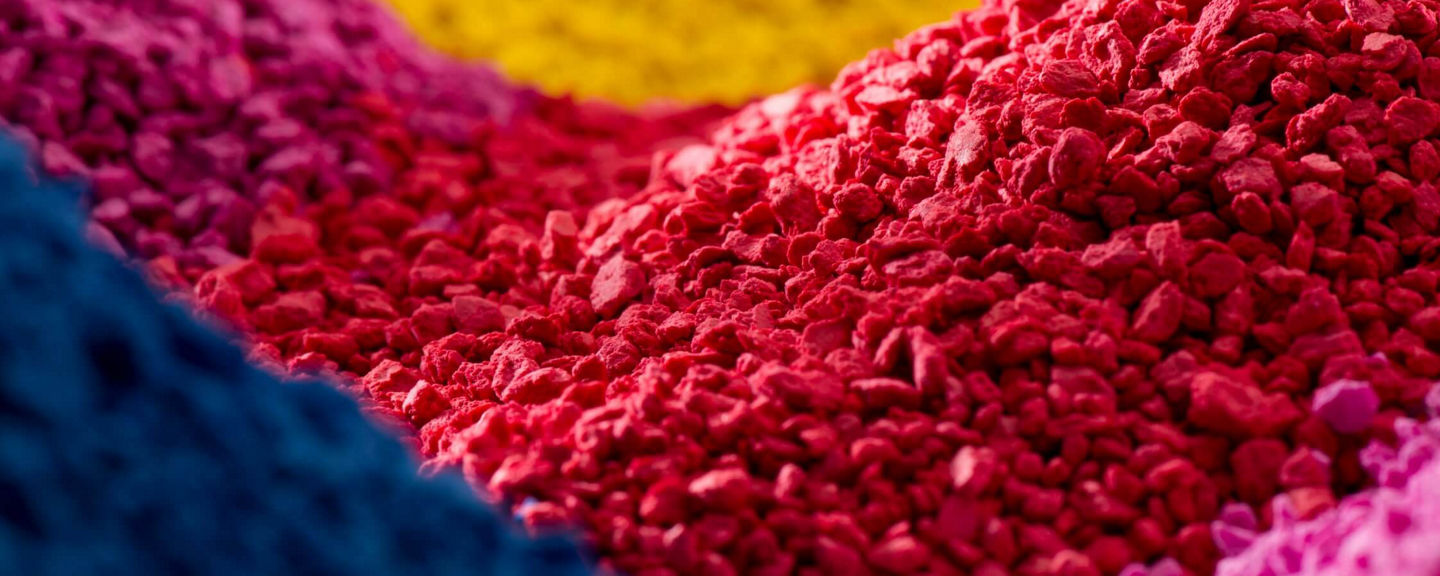 View of multicolored pigment granules in red, blue, pink, and yellow tones, symbolizing innovation and color technology materials.