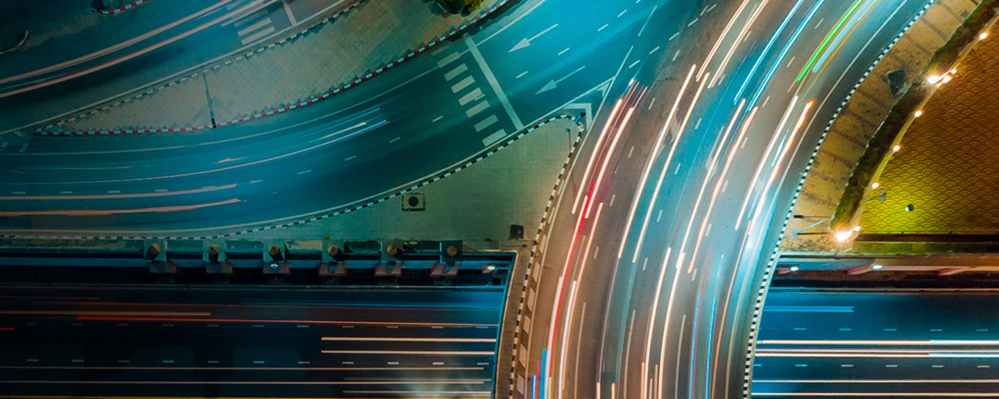 Aerial view of a busy highway interchange at night with streaks of car lights, symbolizing speed, connectivity, and innovation.