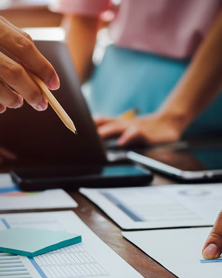 Business professionals collaborating around a desk covered with documents, graphs, and charts during a meeting.