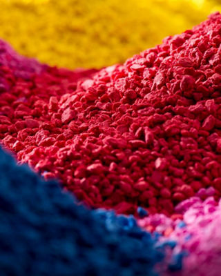 View of multicolored pigment granules in red, blue, pink, and yellow tones, symbolizing innovation and color technology materials.