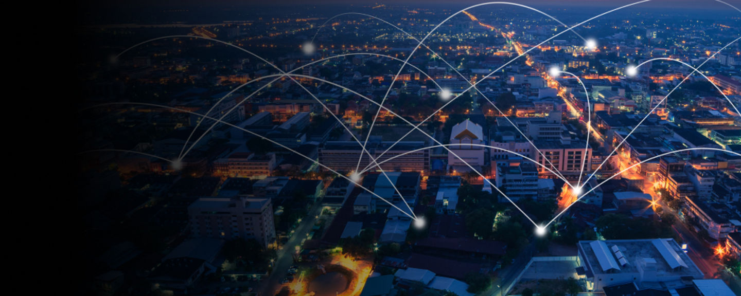 Aerial view of a brightly lit city at dusk with glowing connection lines symbolizing global communication and network connectivity.